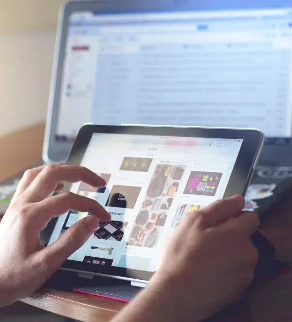 Persona consultando una tienda online en una tableta junto a un ordenador portátil