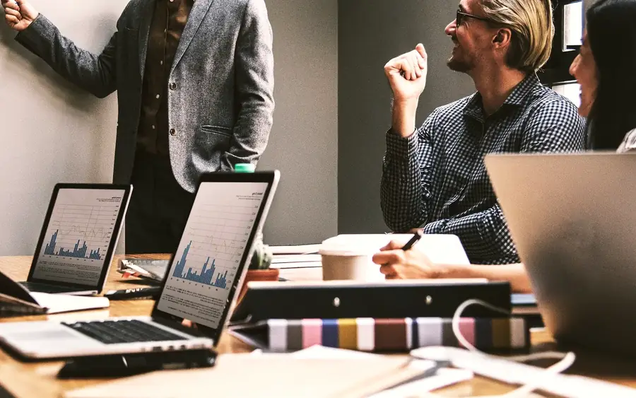 Reunión de trabajo en torno a una mesa con portátiles y gráficos en pantalla